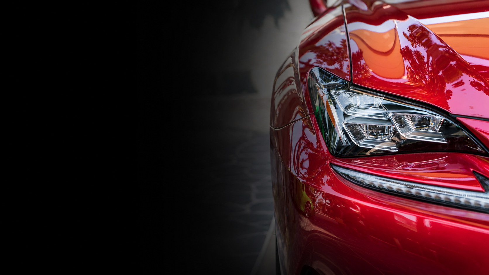 Detalhe frontal de carro esportivo vermelho com pintura espelhada após estética automotiva premium